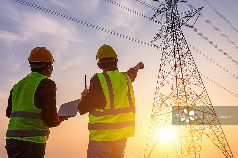 亚洲工程师和工人在标准安全制服下工作，检查高压电线杆图片素材