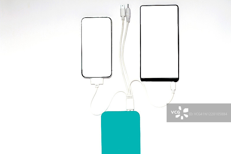 白色背景上用充电宝为智能手机充电图片素材