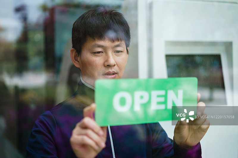 快乐的店主挂起开业标志图片素材