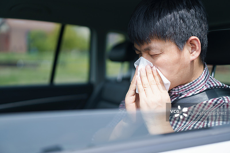 用纸巾擤鼻子的亚洲男人图片素材