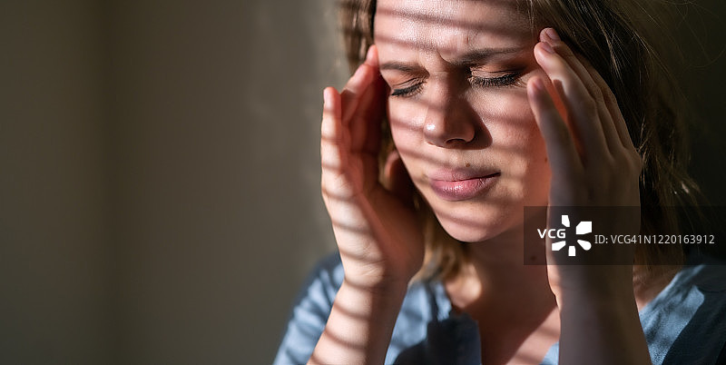 在室内，感到头痛的年轻女性头像图片素材