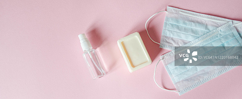 预防各种病毒的个人防护设备——医用口罩、消毒液和肥皂，粉色背景。防护设备banner。复制空间图片素材