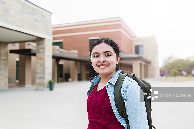 自信的女孩背着背包对着镜头微笑图片素材