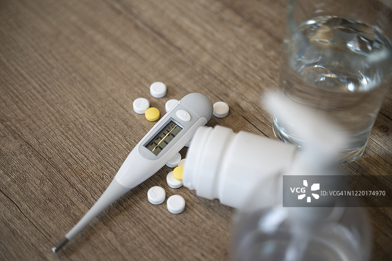 女人手持数字温度计，白色背景，旁边有药丸图片素材