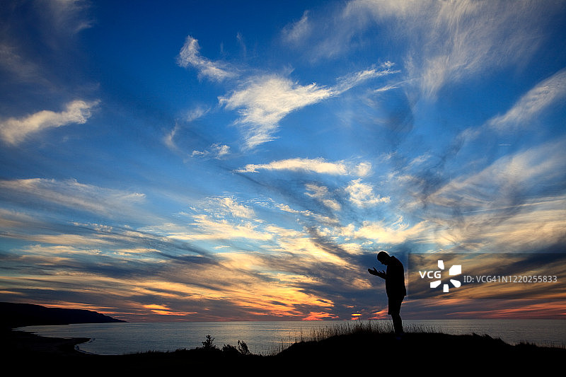 海边日落祈祷的男人剪影图片素材