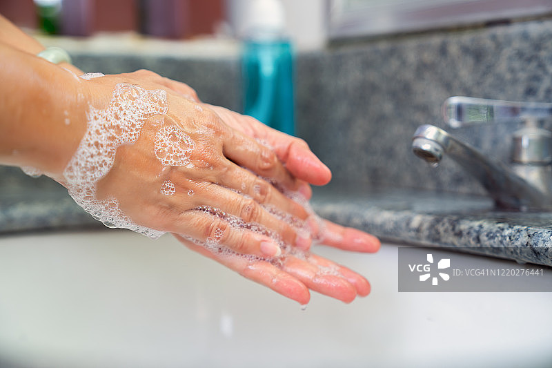 为防止病毒传播，女性用肥皂和水洗手的特写镜头图片素材