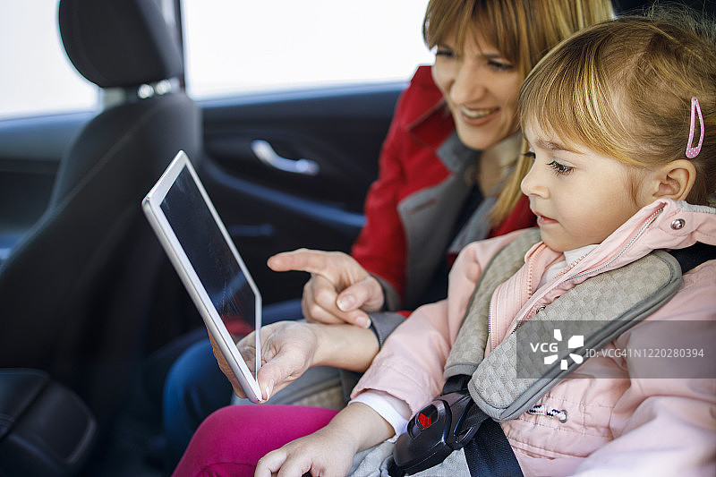 幼童和母亲在车内使用平板电脑图片素材