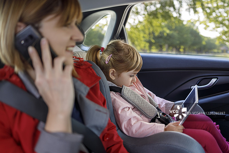 坐在车里使用现代科技的儿童和女人图片素材