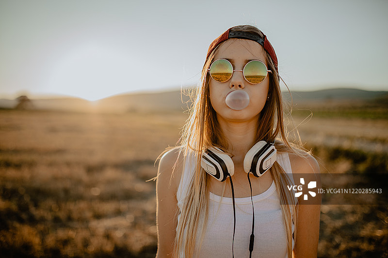 阳光明媚的夏日里吹泡泡糖的少女图片素材