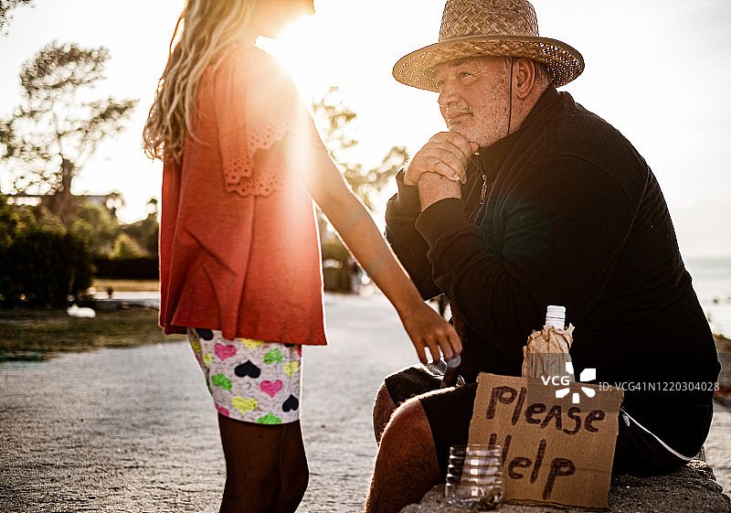 女孩给一个无家可归的男人钱图片素材