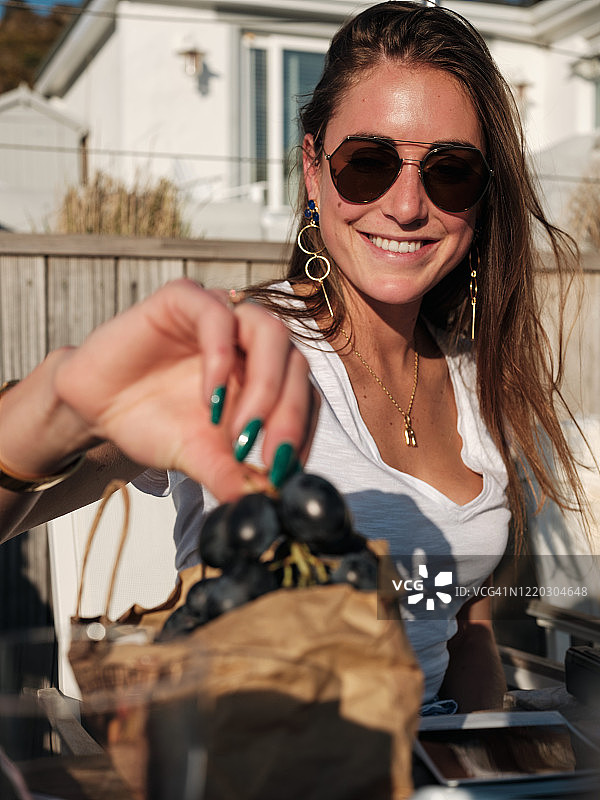 采摘葡萄时微笑的年轻深色头发女子图片素材