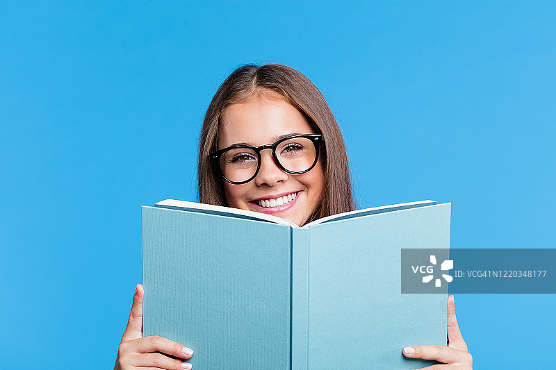 漂亮的少女拿着书挡在脸前图片素材