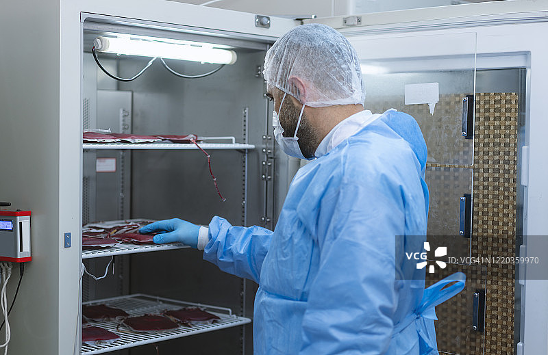 在医院的实验室里，男医生正在检查血袋图片素材
