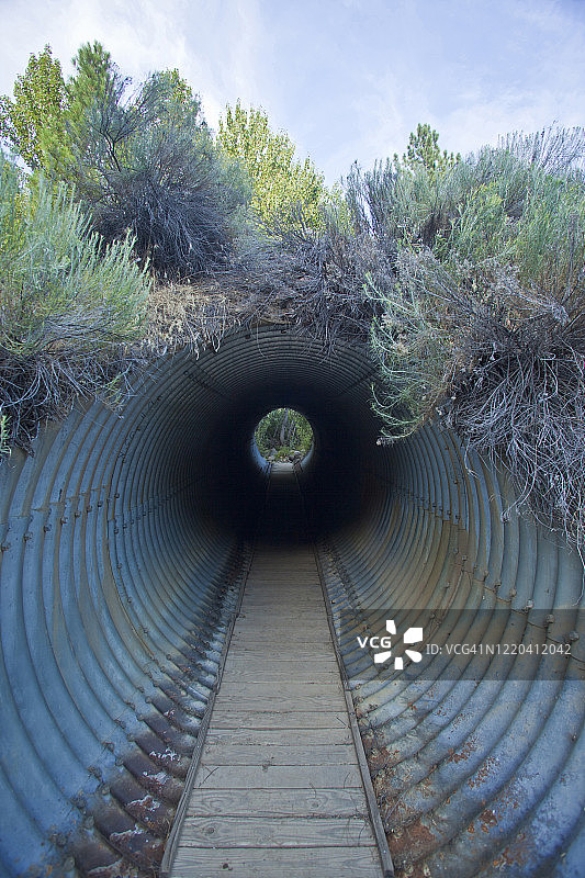 黑暗排水隧道改造成的行人通道，尽头有灯光图片素材