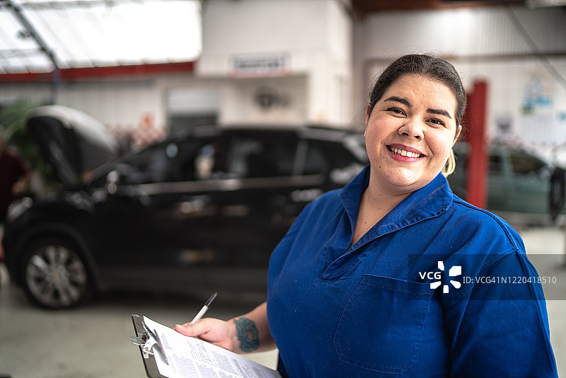 在汽车修理店工作的快乐女人图片素材