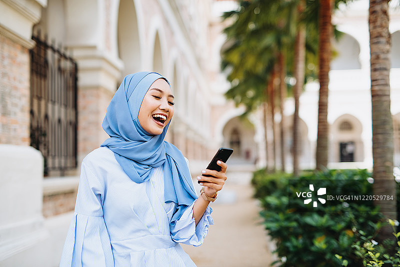 戴着头巾使用智能手机和在线消息的现代穆斯林女性图片素材