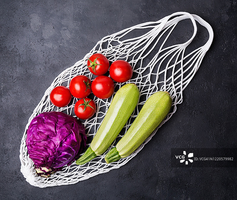 黑色背景下，网兜里的新鲜蔬菜。无塑料，只有天然材料和天然产品。恰当营养与生态理念图片素材