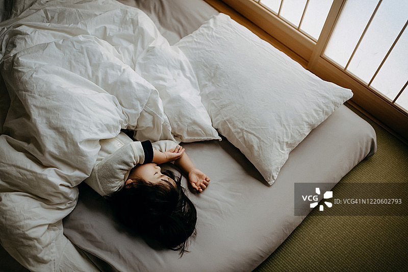亚洲女童在日式传统蒲团上安睡，蒲团铺在家里的榻榻米地板上图片素材