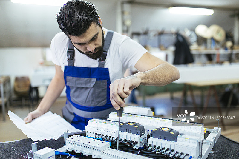 中年维修工在车间维修电子元件图片素材