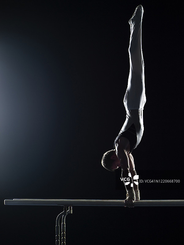 体操运动员在双杠上表演倒立图片素材