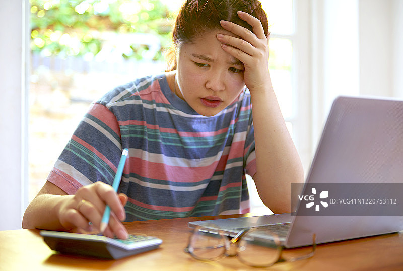 震惊的青少年学生计算信用卡债务图片素材