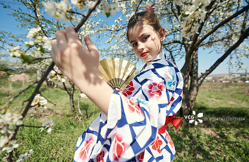 春季梅花林中身穿和服、手持扇子的迷人女孩图片素材