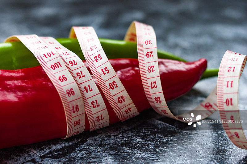 红、青椒一齐用标尺测黑、白背景下的减肥概念图片素材