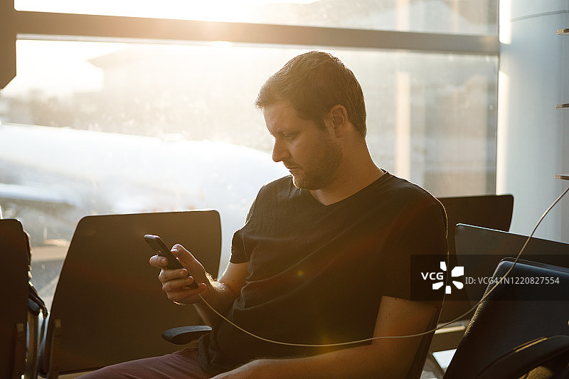 在机场使用智能手机的络腮胡男子图片素材