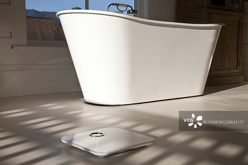 白色大理石地板上的阳光照射下的白色数字浴室秤图片素材