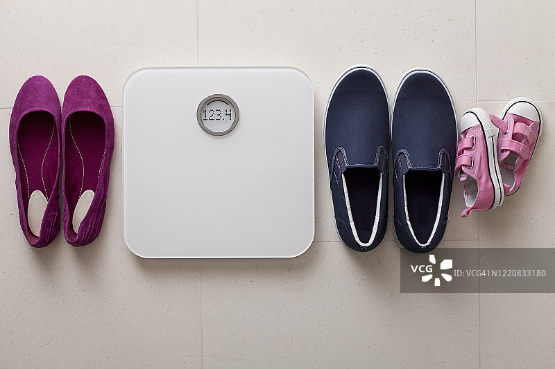 白色大理石地板上的白色数显浴室秤和鞋子图片素材