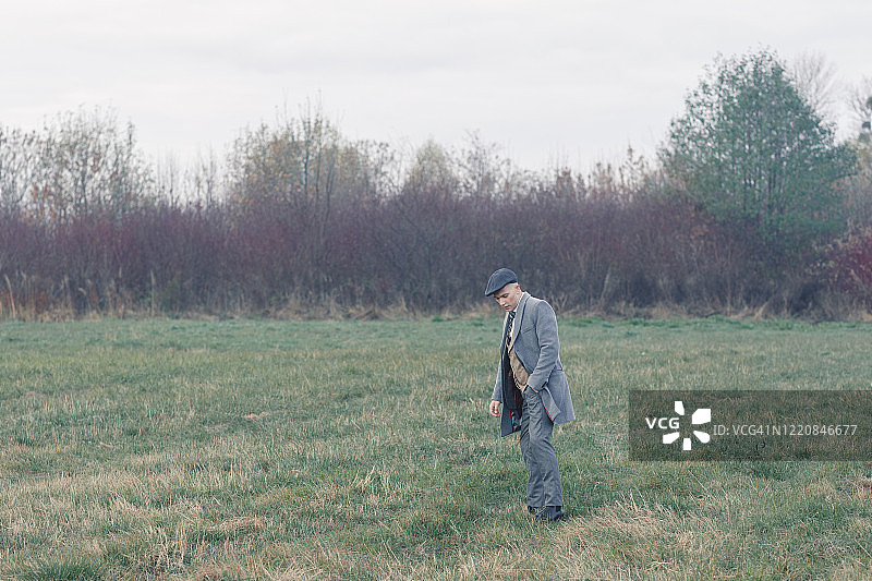 身穿西装的男人独自站在田野里。图片素材
