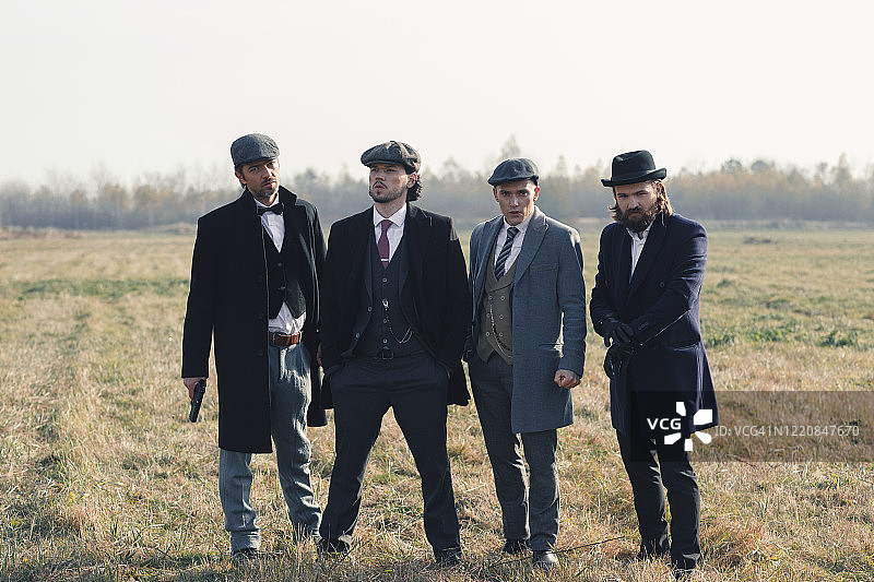 身着复古服装、手持枪支的四位时尚男士图片素材