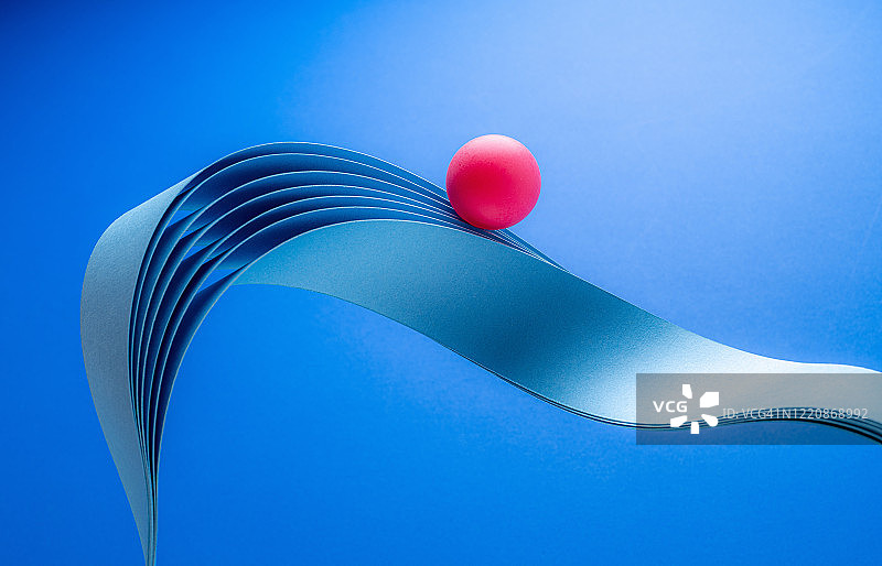 红色球体在纸浪上滚动图片素材