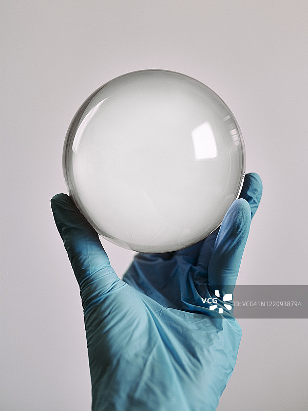 戴蓝色手术手套的手拿着水晶球图片素材