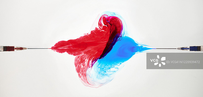 从相对的注射器中喷出时，红蓝色墨水碰撞图片素材