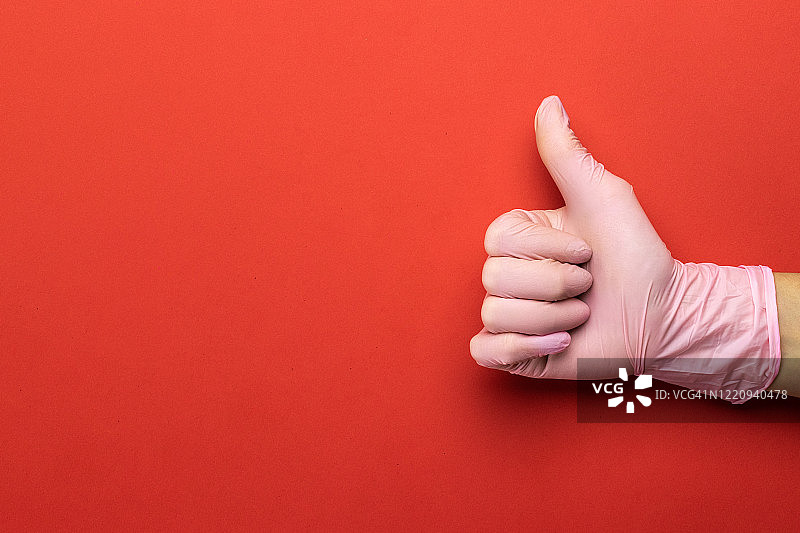 病毒防护：在红色背景上使用医用手套，注意手部清洁，预防新型冠状病毒COVID-19图片素材
