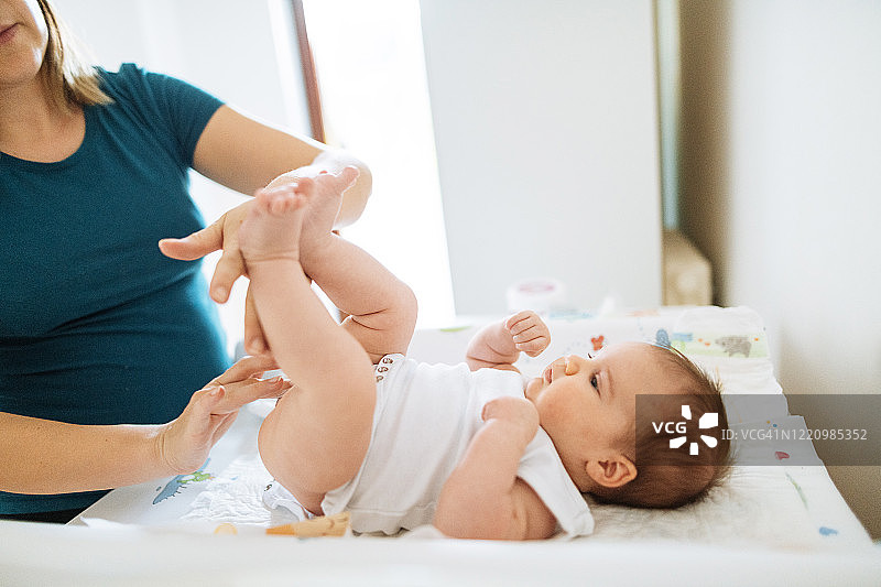 年轻母亲和新生女婴换尿布图片素材