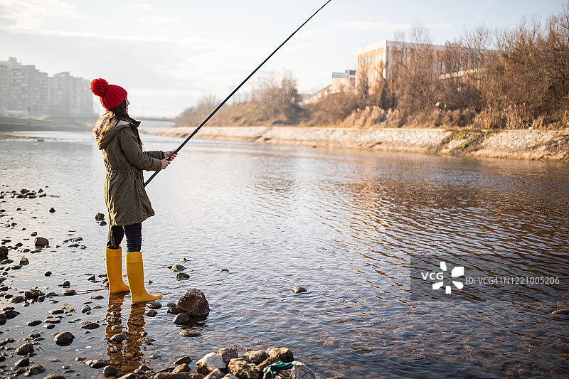 年轻女子站在河里钓鱼图片素材