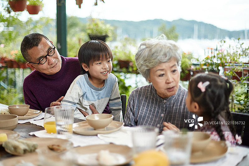 祖父母和孙辈在家庭聚餐时交谈图片素材