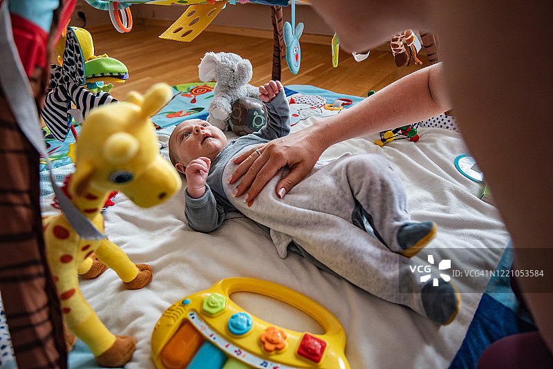 妈妈在家里和可爱的男婴在健身器材上玩耍。图片素材