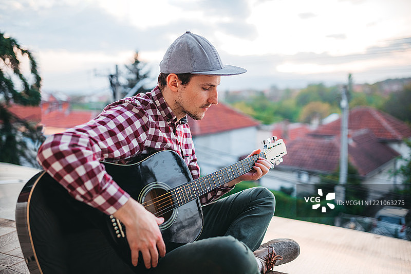 在露台上弹吉他的年轻男人图片素材
