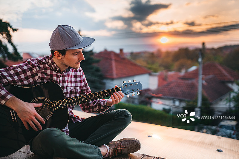 在露台上弹吉他的年轻男人图片素材