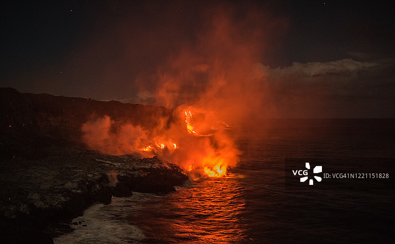 夜晚，炙热的熔岩流入海洋，浓烟滚滚图片素材