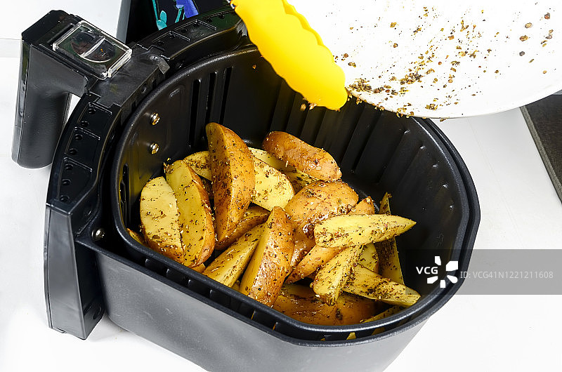 在家用空气炸锅烤土豆，白色背景图片素材