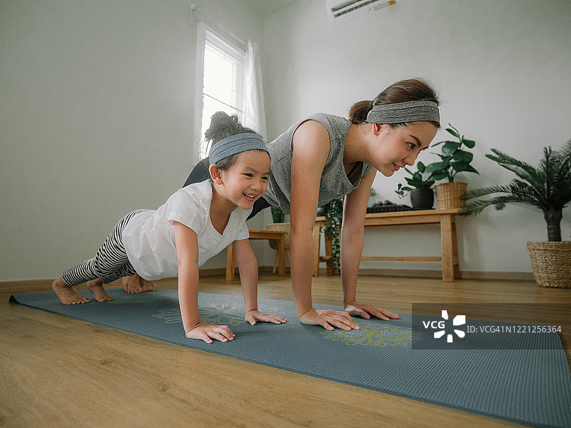 年轻的母亲和女儿在家里做练习。图片素材
