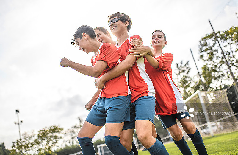 拥抱得分队友的红色球衣足球运动员图片素材