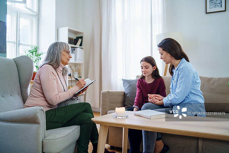 与母亲和治疗师坐在一起交谈的悲伤小女孩图片素材