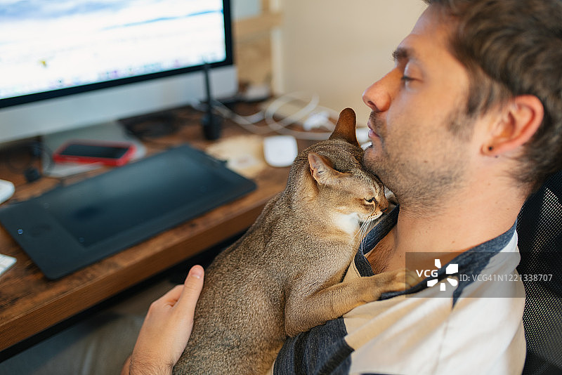 男人在他的家庭办公室里和他的猫小睡图片素材
