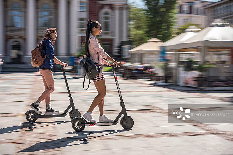 在城市里骑电动滑板车的女人图片素材