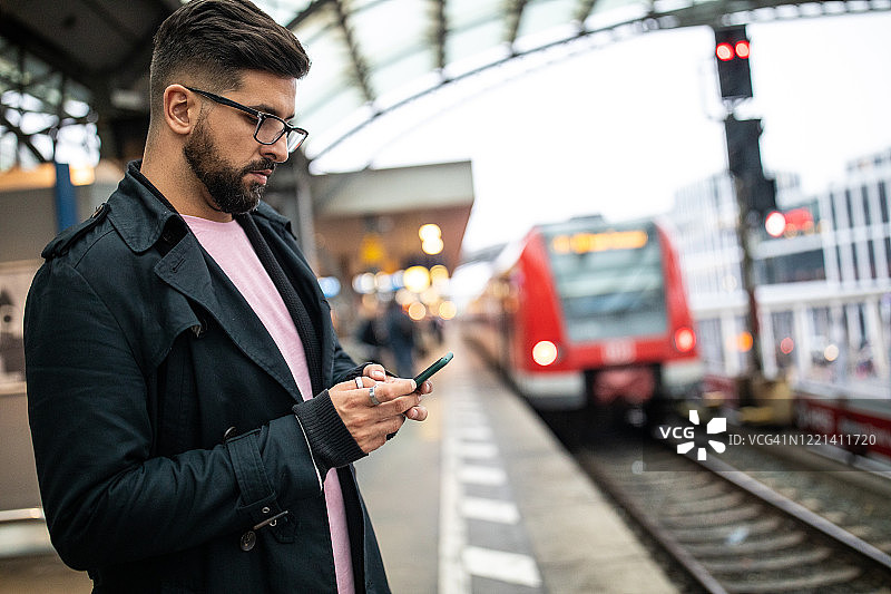 在火车站等火车时使用手机的男人图片素材